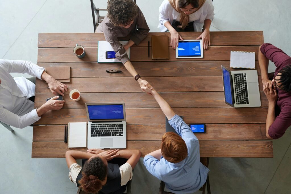 pexels photo 3184306 3184306 1 Overhead view of colleagues in a work meeting using laptops and tablets, emphasizing teamwork and technology.